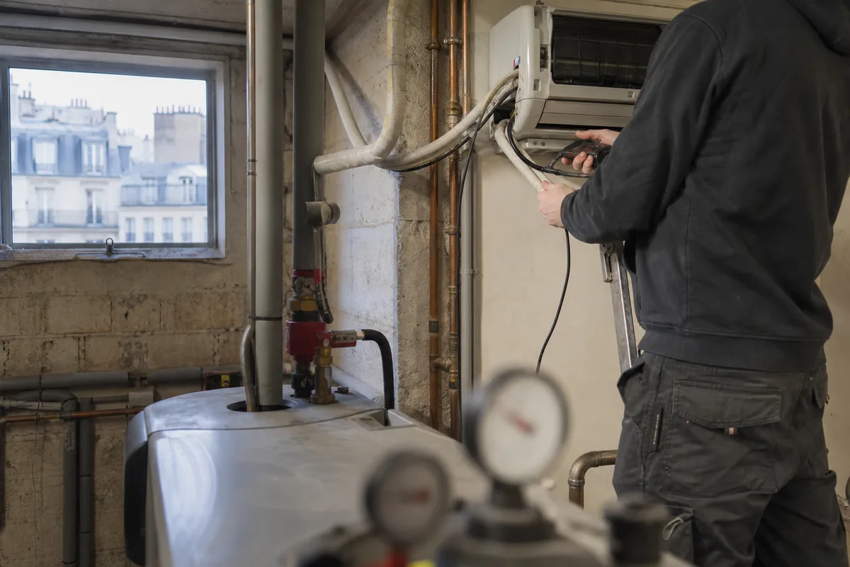Installateur raccordant une unité intérieure de climatisation murale dans un séjour